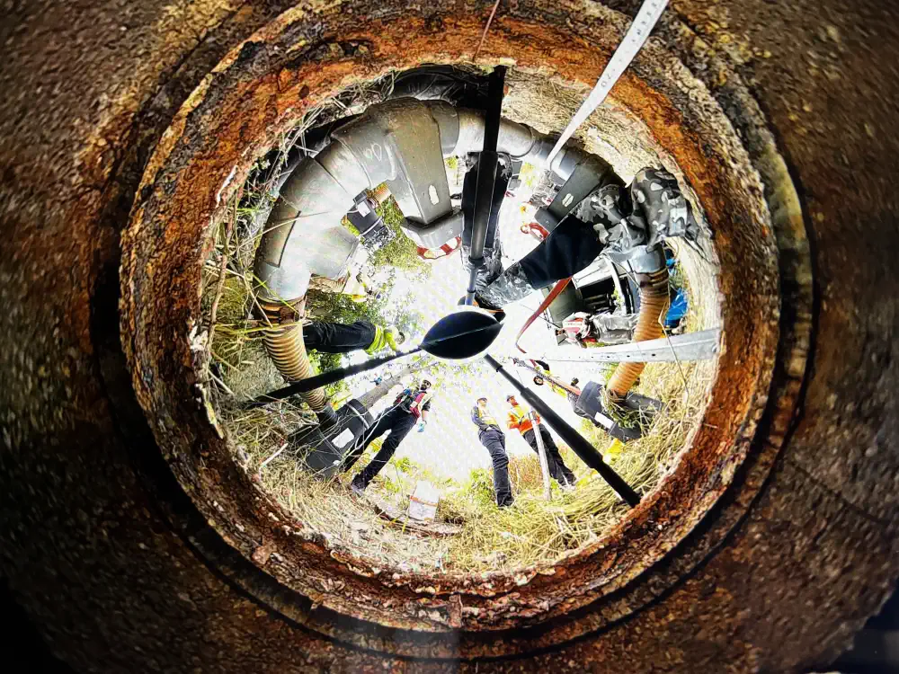 Group of people looking down a manhole
